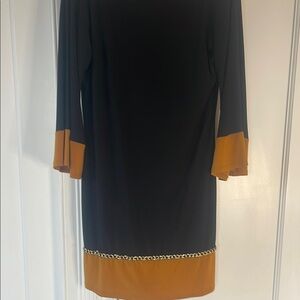 Women’s black dress with mustard color fabric on sleeves and hemline gold chain